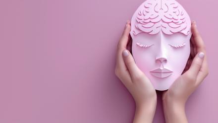 Pink brain mask held in hands against a pink background, representing a creative concept