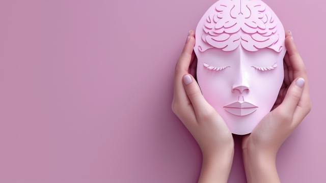 Pink brain mask held in hands against a pink background, representing a creative concept