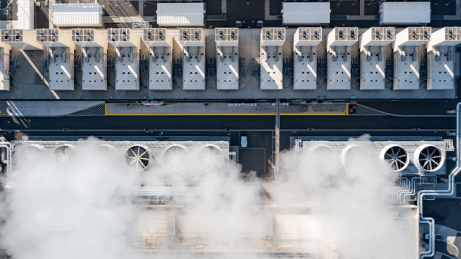 Aerial drone view of large data center cooling systems with industrial fans and steam rising from rooftop infrastructure in The Dalles, Oregon, USA supporting cloud computing and digital technology